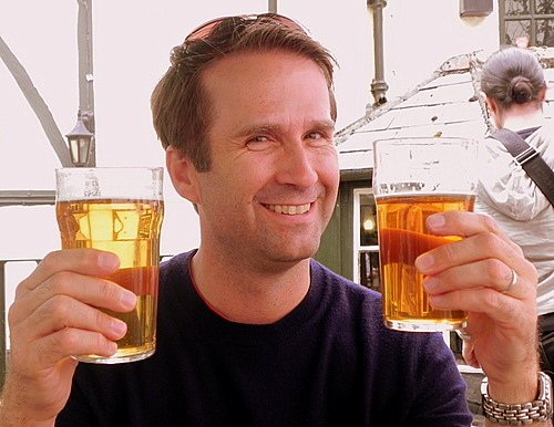 Man smiling holding two beers
