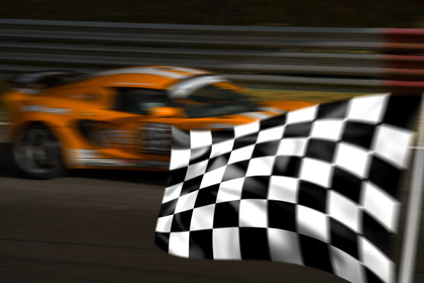 orange race car passing checkered flag