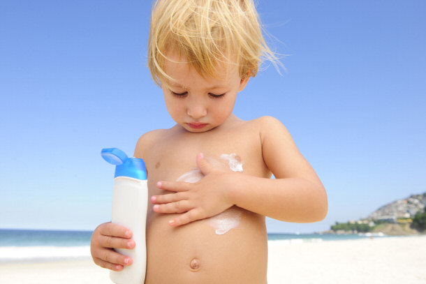 Child applying sunscreen