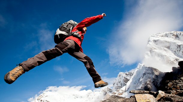 Hiker jumping over cliff