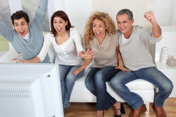 adults sitting and wtaching with friends on their couch