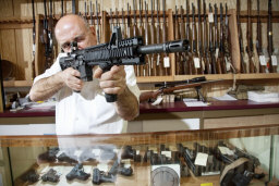 man in gun shop aiming assault rifle